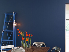 Industrial chic blue feature wall with dark timber table and metal chairs with ladder and flowers